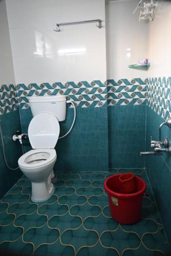 a bathroom with a toilet and a red bucket at Ramleela Stay, Gokarna in Ankola