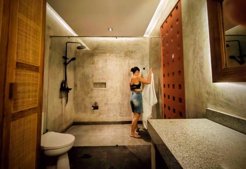 a woman standing in a bathroom with a shower at Pigstone Design Studios Beachfront in Tanah Lot