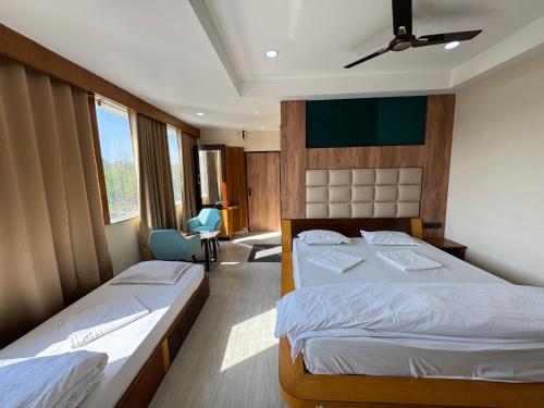 a bedroom with two beds and a chair at Hotel M Plaza New Digha in Digha