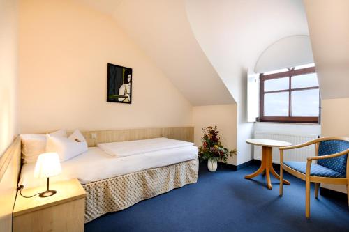 a room with a bed and a table and a chair at Kim Hotel Dresden in Dresden