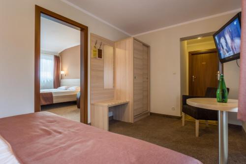 a hotel room with a bed and a table and a television at Pensjonat Carmen in Szklarska Poręba