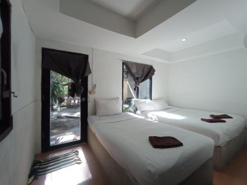 two beds in a room with a window at The Relax Resort in Ko Phangan