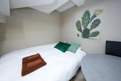 a bedroom with a white bed with a cactus painting on the wall at Ra Grande by Tranova in Tokyo