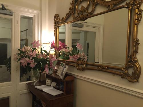 a mirror on a wall next to a table with flowers at Chester House Guest House in Chester