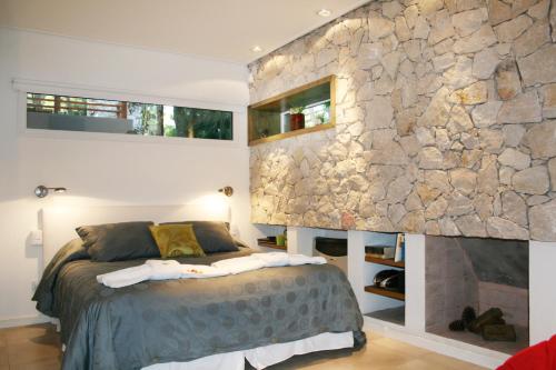 1 dormitorio con cama y pared de piedra en Kaia Apart y Spa en Mar de las Pampas