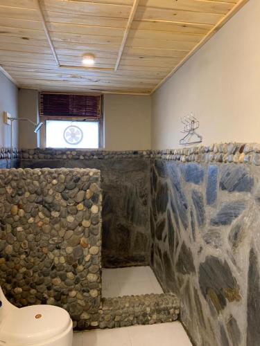 a bathroom with a stone wall and a toilet at Zimsa Resort Skardu in Skardu