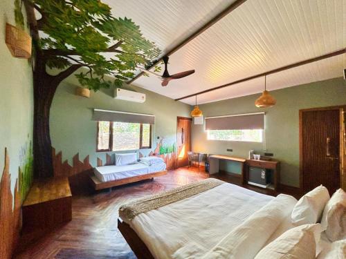 a bedroom with a tree painted on the wall at Tadoba Jungle Camp in Mohurli