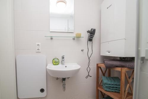 a white bathroom with a sink and a mirror at Leichte Brise 2 Greetsiel in Krummhörn