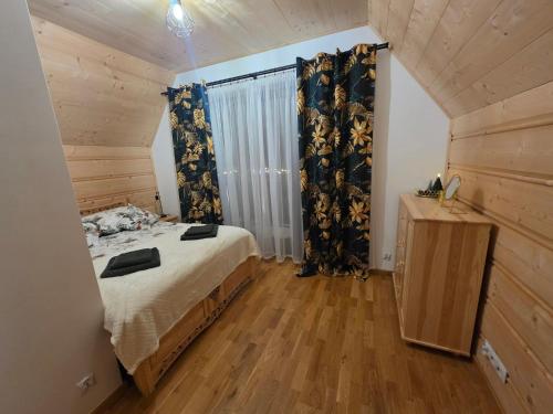 a bedroom with a bed and curtains and a wooden floor at Family House B in Witów