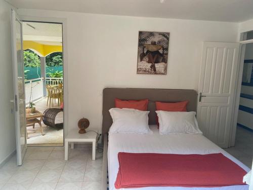 a bedroom with a bed with a red blanket on it at Mon petit coin de paradis in Morne-à-lʼEau