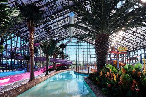 a large indoor swimming pool with palm trees in a building at Sibenik Resort in Šibenik