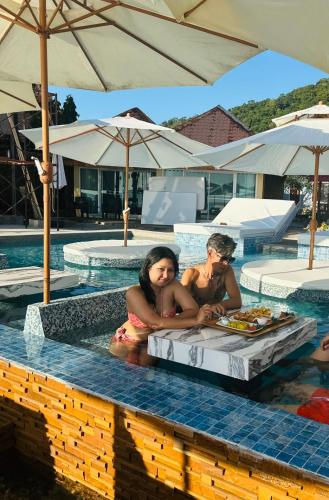 two people sitting in the water in a swimming pool at Exclusive Bungalow Near Swiming Pool At Kohchang Resort in Ko Chang
