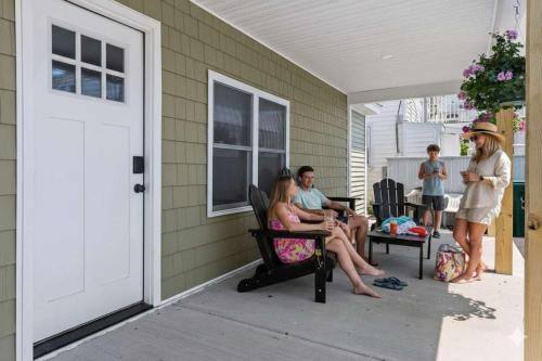 a group of people sitting on the porch of a house at Steps to Beach Fully Renovated Sleeps 6 in Hampton