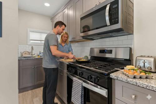 a man and woman preparing food in a kitchen at Fully Renovated Steps to Beach The Americana in Hampton