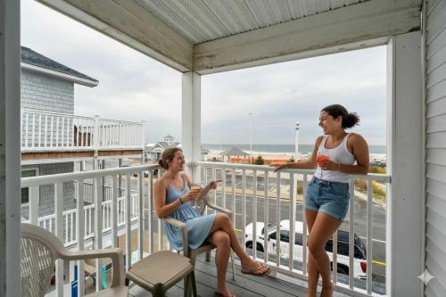 two women on a porch with the ocean in the background at Newly Renovated Private Balcony Steps to Beach in Hampton