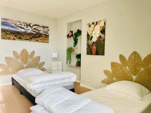 two beds in a room with paintings on the wall at Agréable bastide provençale avec piscine in Barcelonne