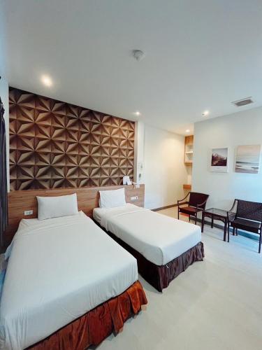 two beds in a room with two chairs at Seree Grand Resort in Hat Yai