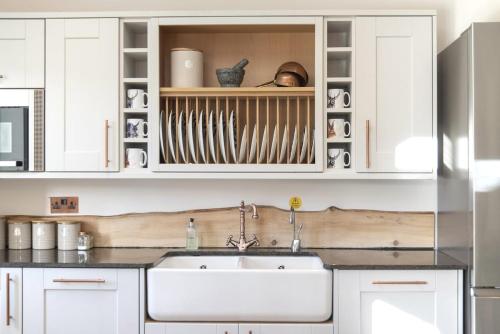 a kitchen with white cabinets and a sink at The Steading InThePark in Stirling