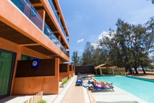 - un groupe de personnes dormant sur des chaises au bord de la piscine dans l'établissement Coriacea Beachfront Boutique Phuket Resort, à Mai Khao Beach