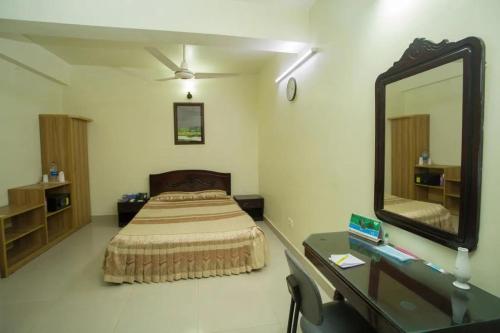 a bedroom with a bed and a mirror and a desk at City Inn Ltd in Khulna