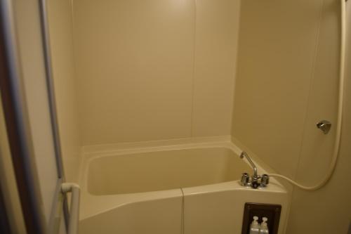a bath tub in a bathroom with a shower at Ryokan Fukuzen in Shibukawa