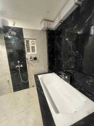 a bathroom with a white tub and a black wall at Alishba Hotel And Restaurant in Lālbāgh