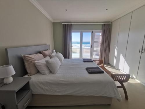 a bedroom with a bed with a view of the ocean at Central, Beachfront Home in Jeffreys Bay
