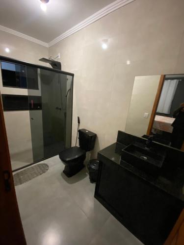 a bathroom with a black toilet and a sink at Casa amarela in Santana do Riacho