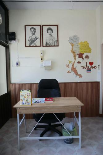 a wooden desk with a chair and pictures on the wall at HOM's HOSTEL in Phuket