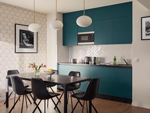 a kitchen with blue cabinets and a table and chairs at YAYS Paris Issy by Numa in Issy-les-Moulineaux