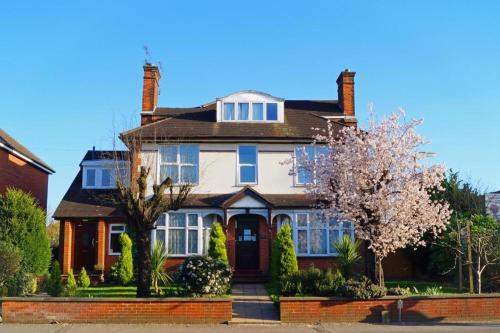 a large house with a flowering tree in front of it at Ricky Road Guest House in Watford
