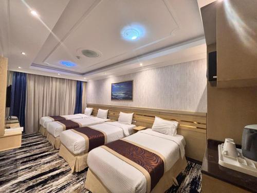 a hotel room with four beds and a television at فندق مواسم الاحسان توصيل مجانى للحرم in Al ‘Azīzīyah