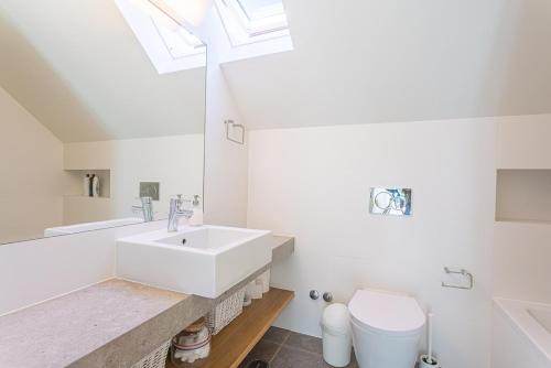 a bathroom with a sink and a toilet and a skylight at Villa Santamaria in Colares