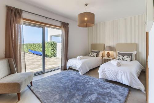a living room with two beds and a balcony at Villa del Rey II in Casal da Lagoa Seca
