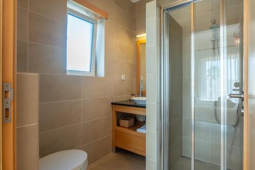 a bathroom with a toilet and a glass shower at Villa del Rey VII in Casal da Lagoa Seca