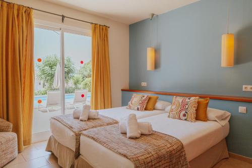 two beds in a bedroom with a view of a pool at Villa Santo Tomás - Loli in Santo Tomás