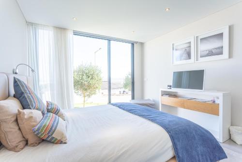 a white bedroom with a large window and a bed at Villa Sao Martinho in São Martinho do Porto
