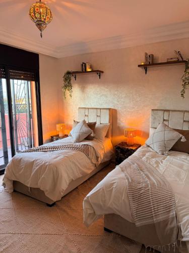 a bedroom with two beds and a chandelier at Charming Bohemian hideaway in Marrakech in Marrakesh