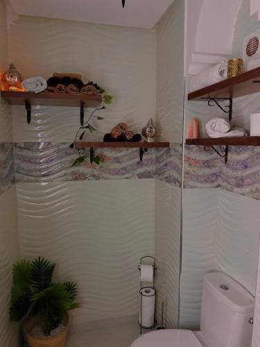 a bathroom with a toilet and shelves with towels at Charming Bohemian hideaway in Marrakech in Marrakesh