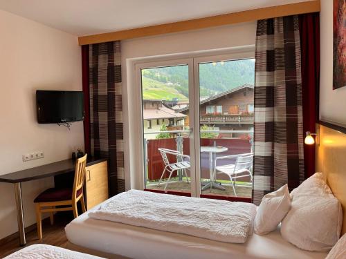 a bedroom with a bed and a large window with a patio at Sporthotel Bergheim in Sölden