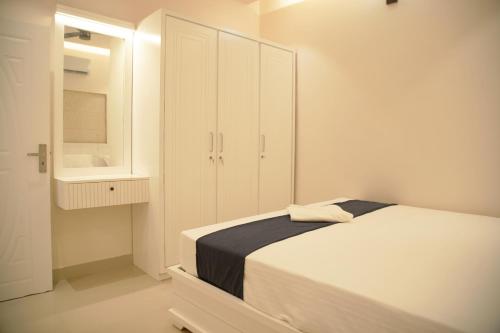 a white bedroom with a bed and a cabinet at Gentur Enclave in Mananthavady