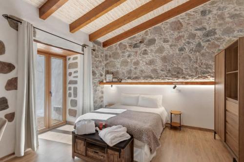 a bedroom with a bed and a stone wall at La Pelusa casa rural in La Culata