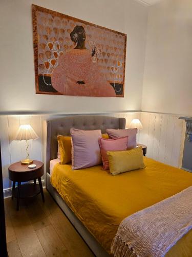 a bedroom with a yellow bed with colorful pillows at CERULEAN HOUSE - Iconic Renovated Period Home - Close to Everything in Bendigo