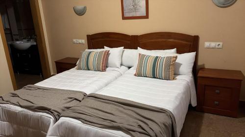 a bedroom with two beds with white sheets and pillows at Ruralis Altozano in Montánchez