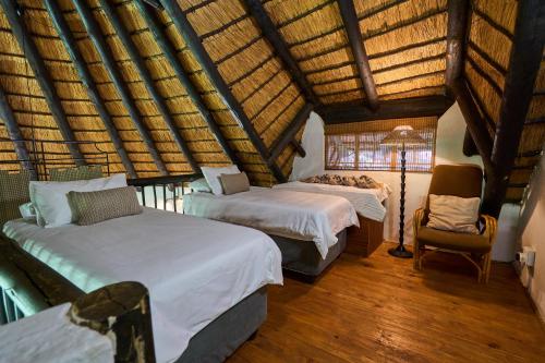 ein Schlafzimmer mit zwei Betten, einer Lampe und einem Stuhl in der Unterkunft Sable Ranch Selfsorg in Brits