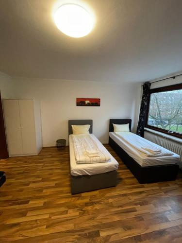 two beds in a room with a large window at Studio Apartment mit Balkon in Neumünster