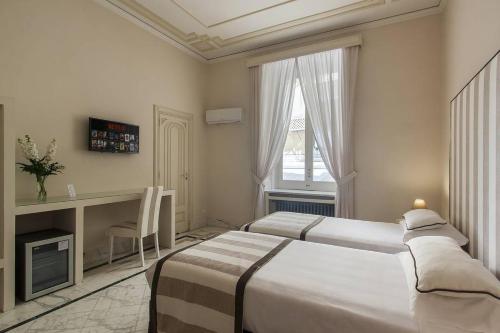 a bedroom with two beds and a desk and a window at Otium in Sorrento in Sorrento