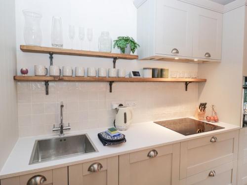 a kitchen with white cabinets and a sink at The Wonky Nest in Windermere