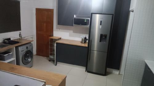 a kitchen with a stainless steel refrigerator and a washing machine at Bushman Kraal Lux in Soweto
