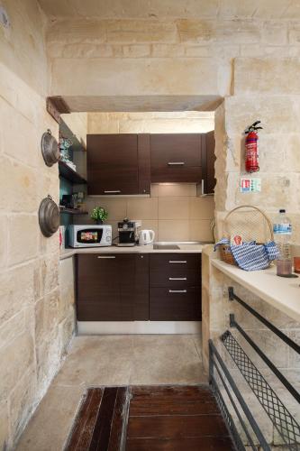 a kitchen with brown cabinets and a stone wall at Traditional Maltese 2-Bedroom Home with Private Hot Tub - Steps Away from Valletta in Il-Furjana